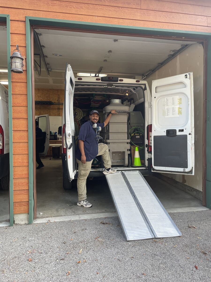 A uniformed, NADCA-certified SafeAir Duct Care technician with negative-pressure cleaning equipment at the company van